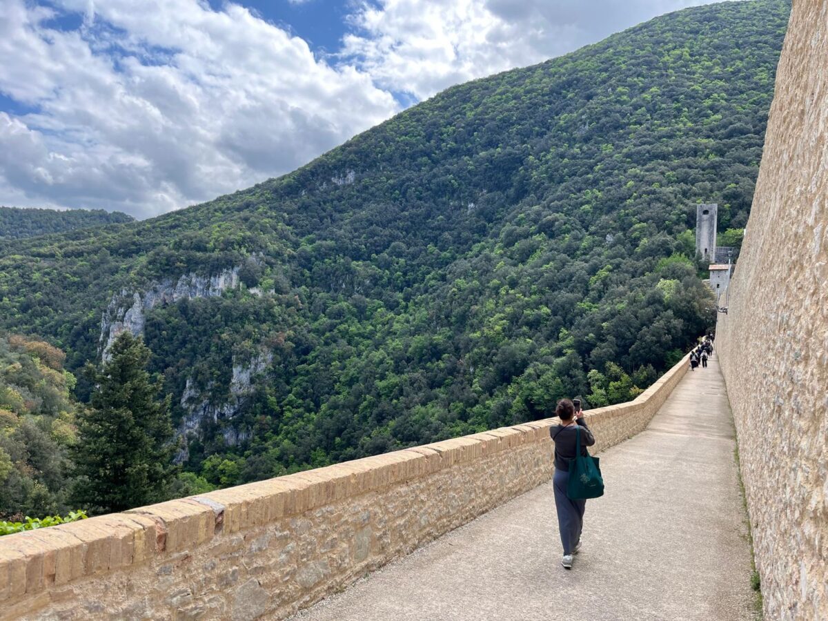 Tourists walking and cycling across Ponte delle Torri in Spoleto after reopening