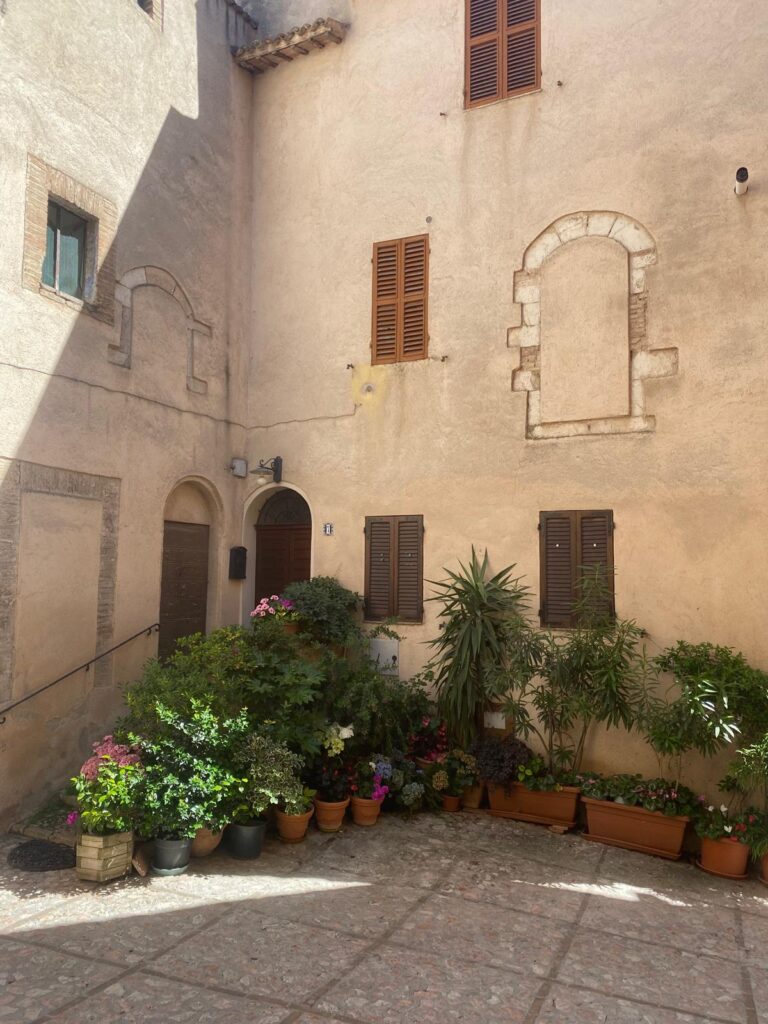 Stone wall with a central window inside an internal yard of a historic house in Trevi, Umbria, Italy