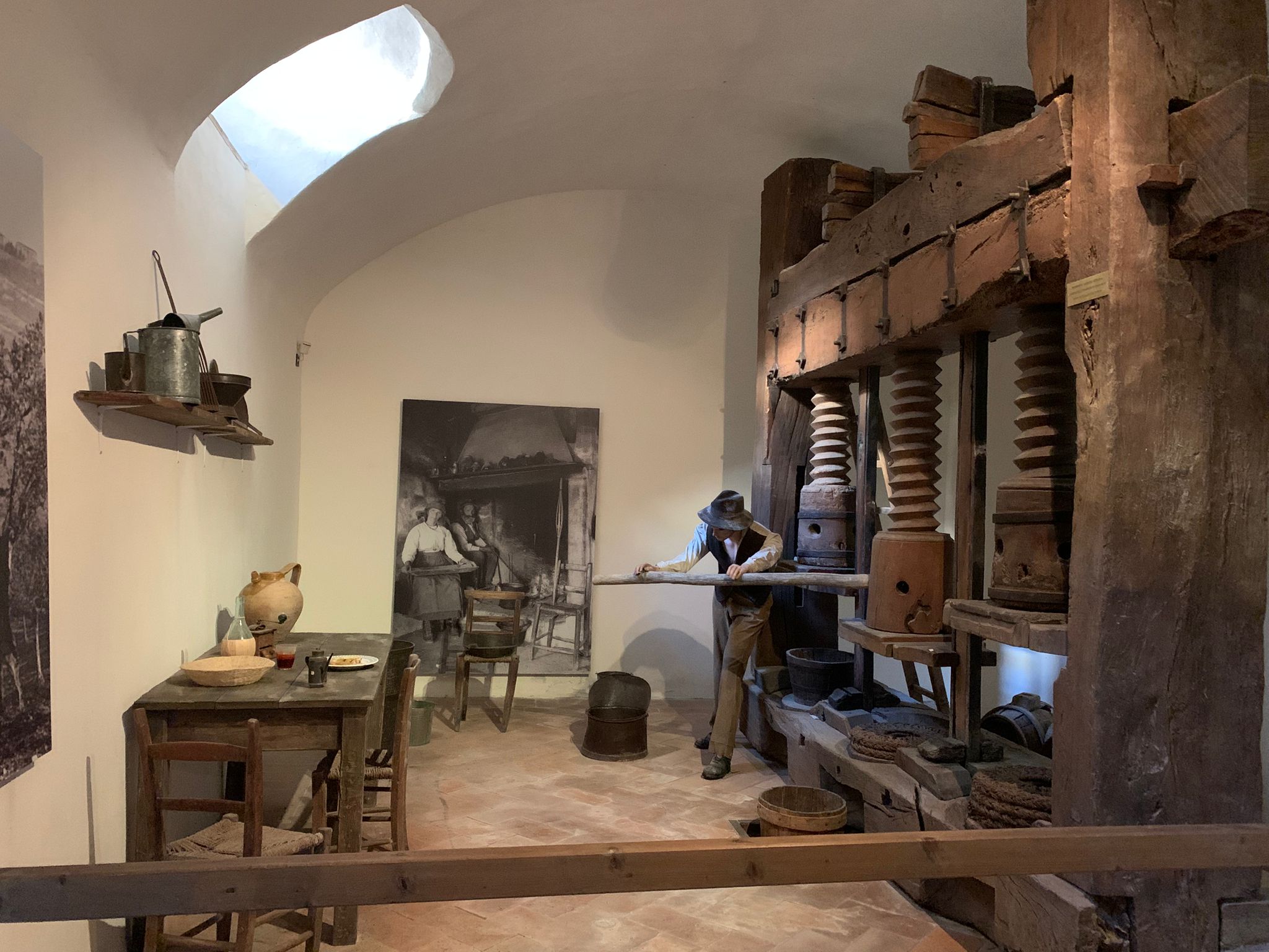 Exhibit inside the Olive Oil Museum in Trevi showing traditional tools and a worker mannequin