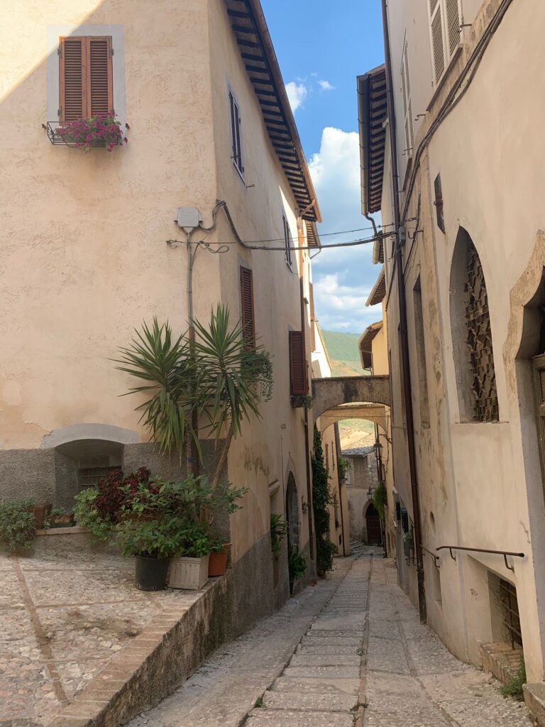 Narrow stone street in the historic center of Trevi, Umbria, Italy, with medieval houses and warm sunlight