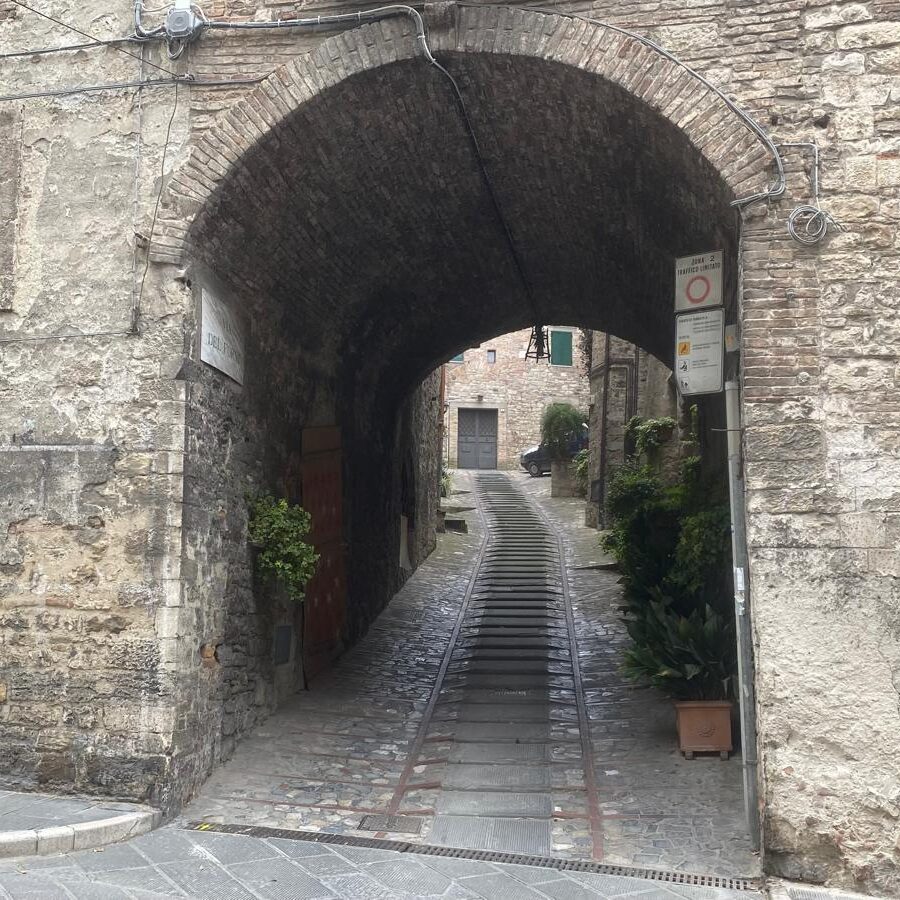 Historic street in Todi with stone arch and uphill stairs