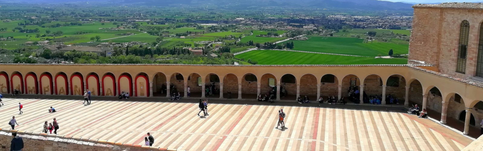 Panoramic view of the Basilica of Saint Francis of Assisi overlooking the Umbrian countryside.